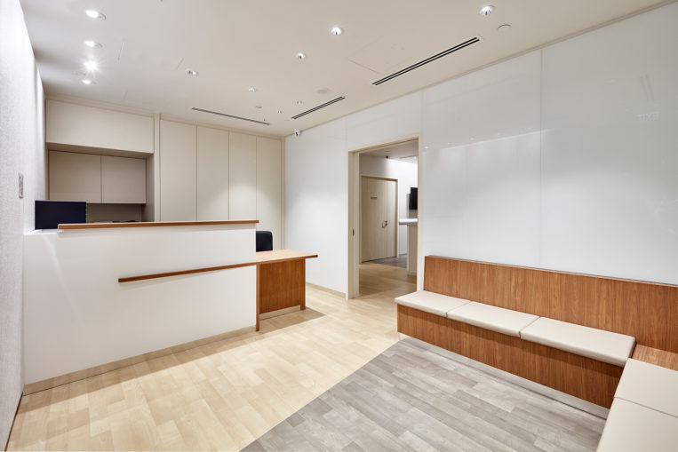 Novaptus Surgery Centre, the reception area is contemporary, sharp with acoustic wall panelling and white colour-backed glass. The space is transient and relatively small, so the material selection helps to make the space feel larger.