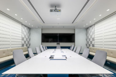 Q2 Solutions main conference room in Singapore. The high performance space includes a graphic reference to the Singapore skyline to orientate visitors when dialling in for video conferencing. Bold blue colours and waterfall acoustic panel details provide visual interest.